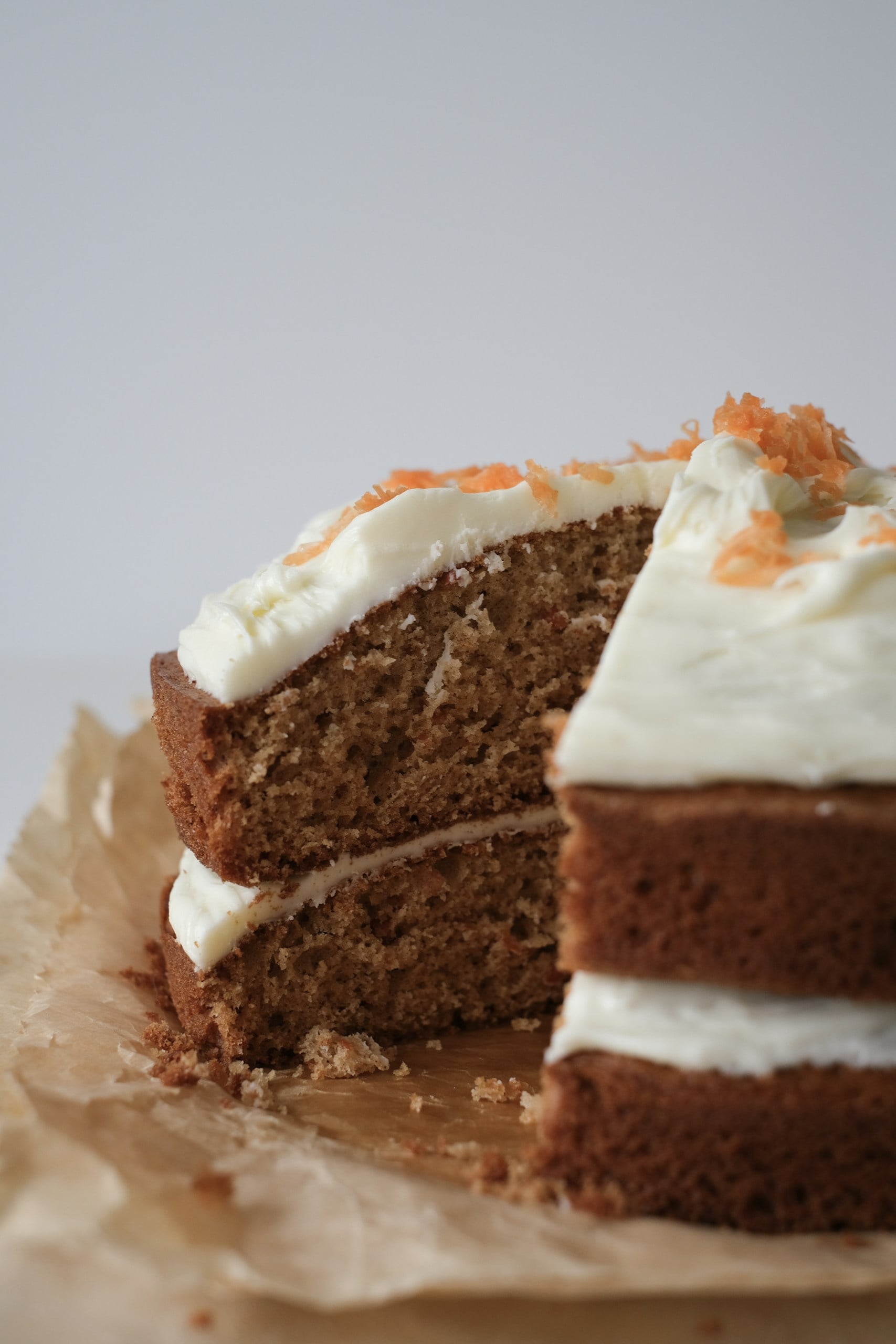 naked carrot cake on parchment paper with a slice cut out