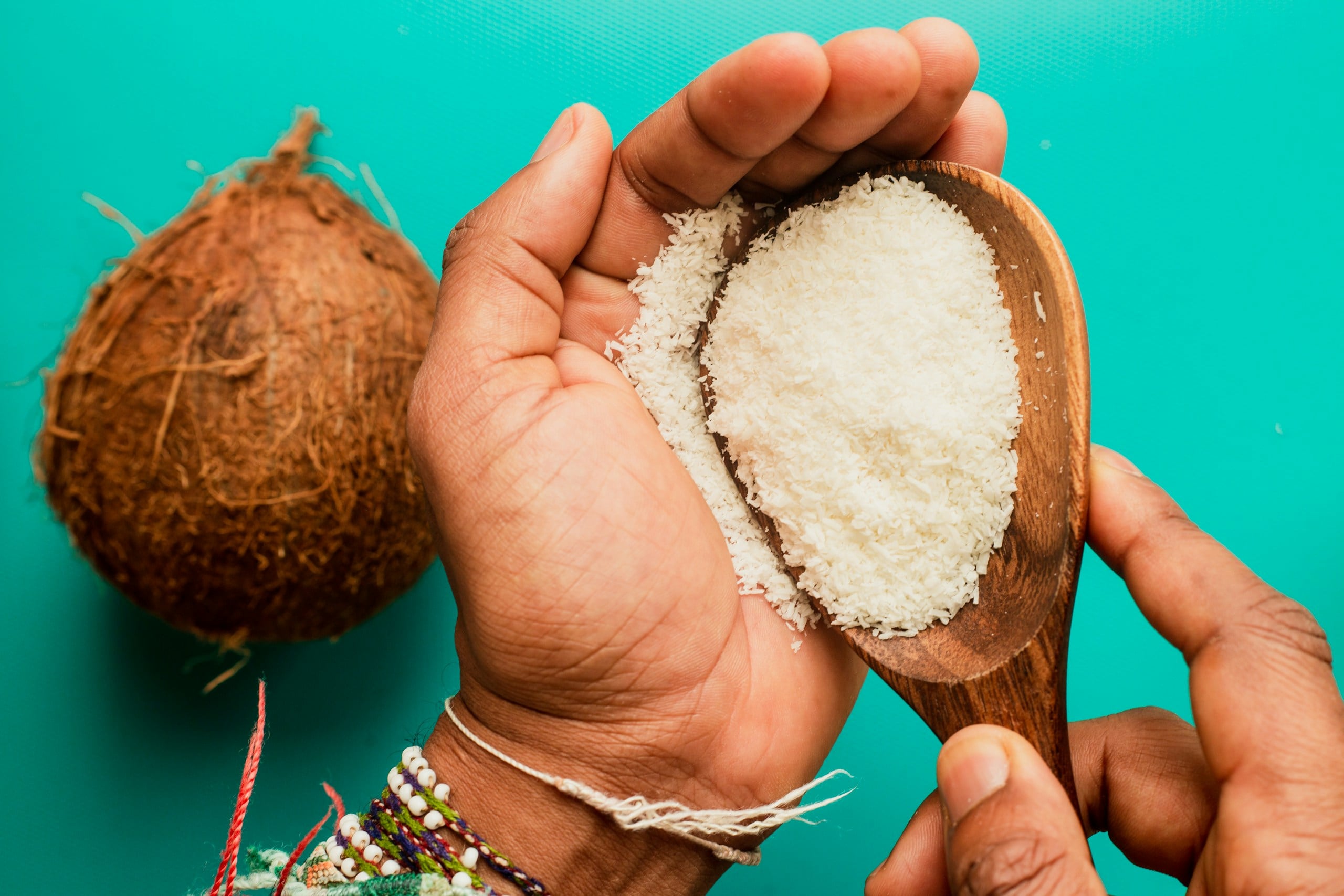 Person holding shredded coconut/powder next to a coconut