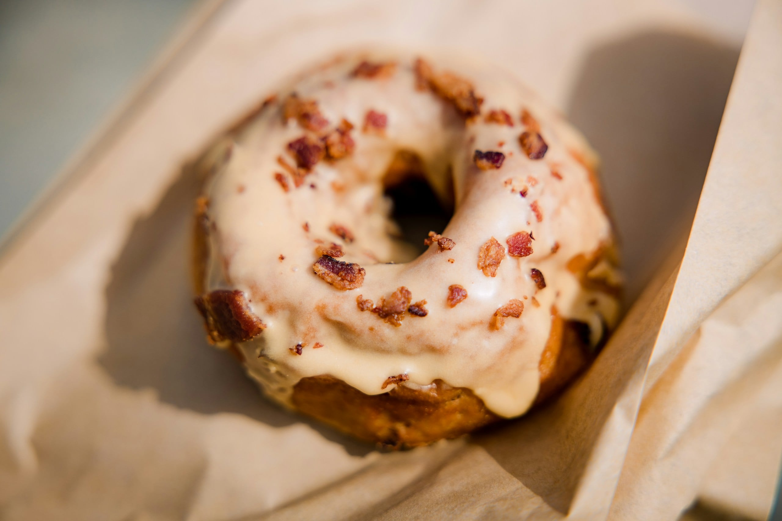 A gluten-free pumpkin donut coated with vanilla glaze and crushed nuts 
